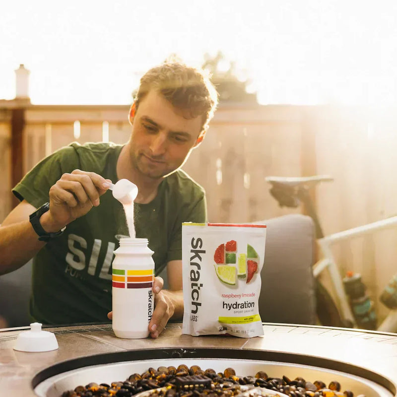 cyclist pouring hydration mix into a bottle